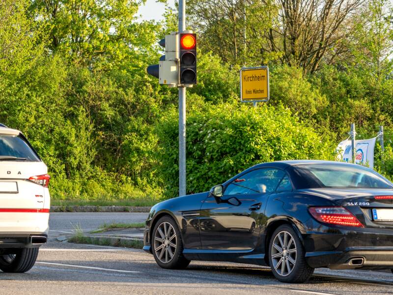 Gezeigt wird eine Kreuzung im Gemeindegebiet Kirchheim, an welcher Autos warten. Im Hintergrund sieht man das Ortsschild.